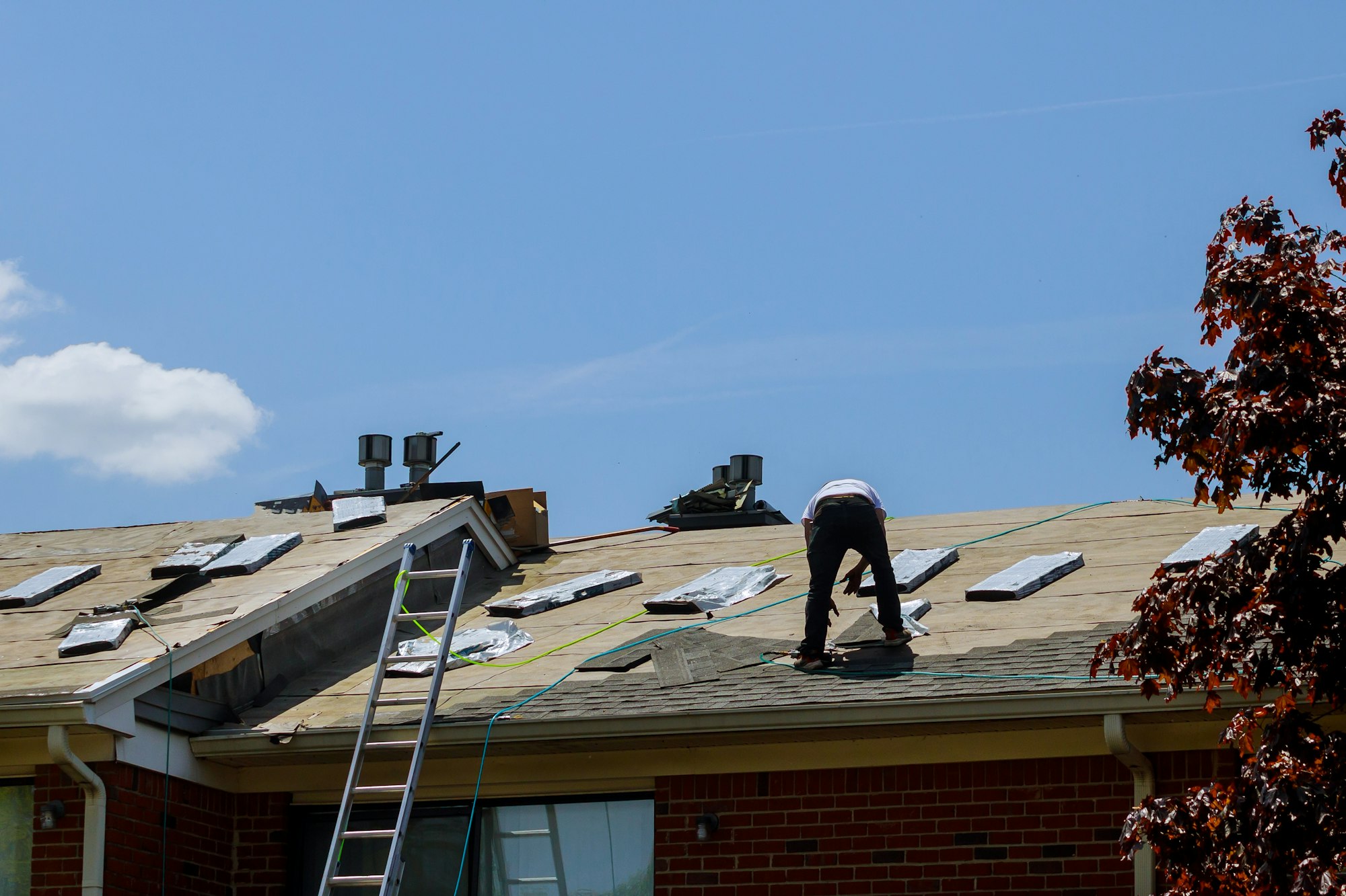 Roof repair, worker with replacing gray tiles shingles on house being applied